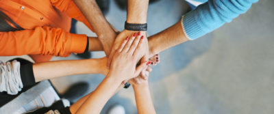 Top view image of group of young people putting their hands together. Friends with stack of hands showing unity.