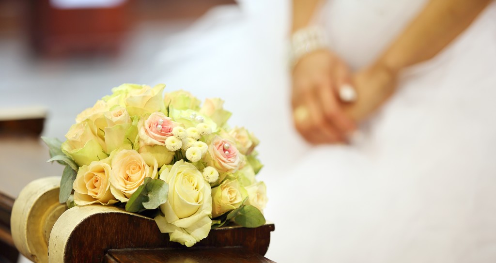 Bridal wedding bouquet lying on the hassock during the marriage ceremony